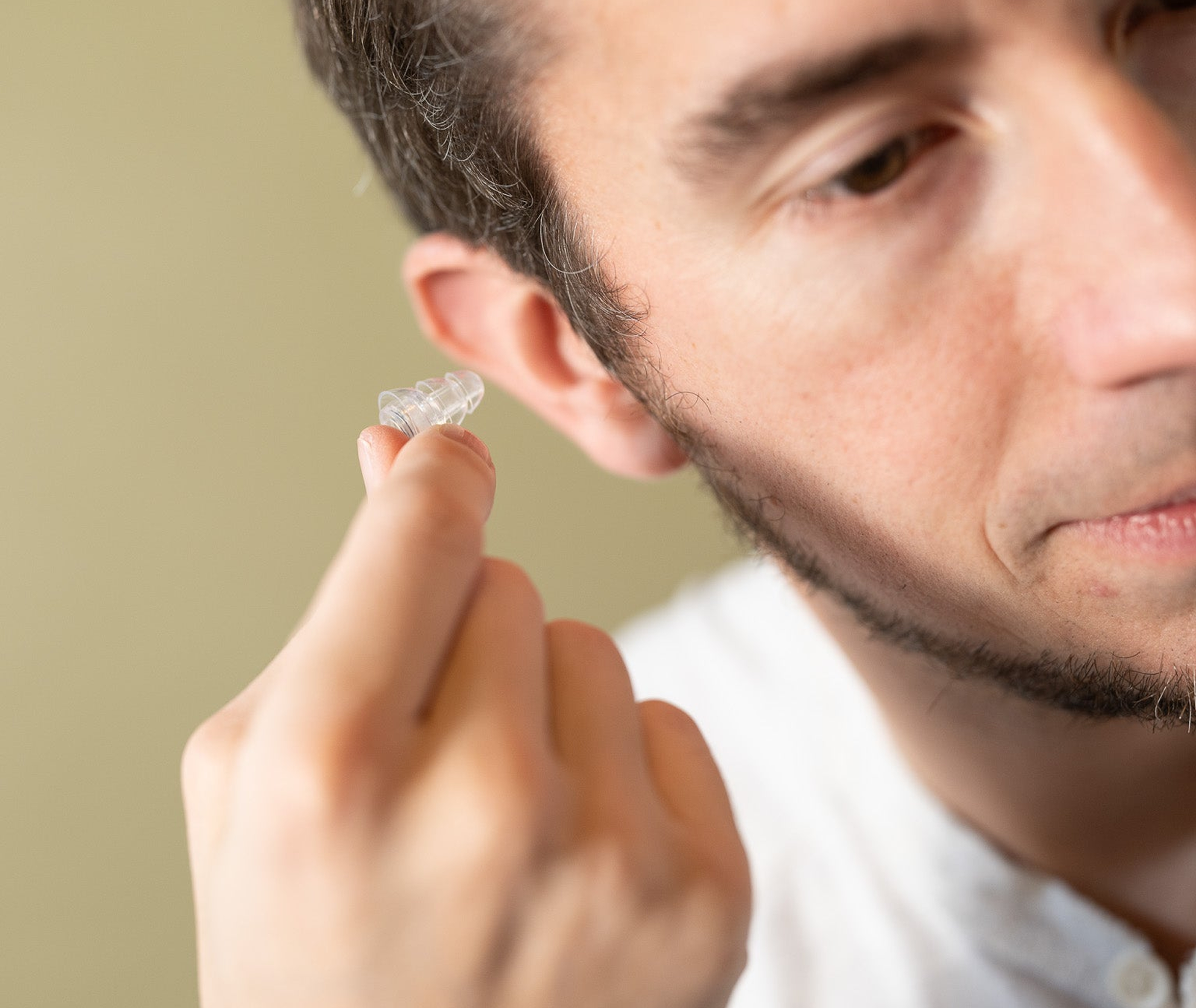 A man places Ear-Goes high fidelity silicone earplugs in his ear.