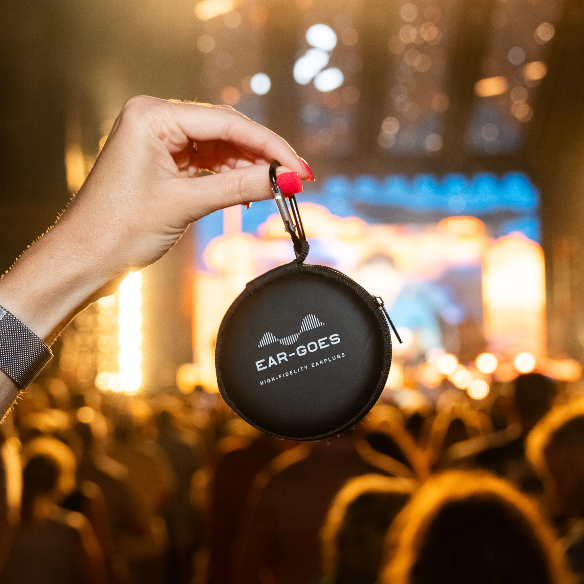 A woman's hand holds an Ear-Goes zippered earplug case at a CMA Country Music Award Festival concert