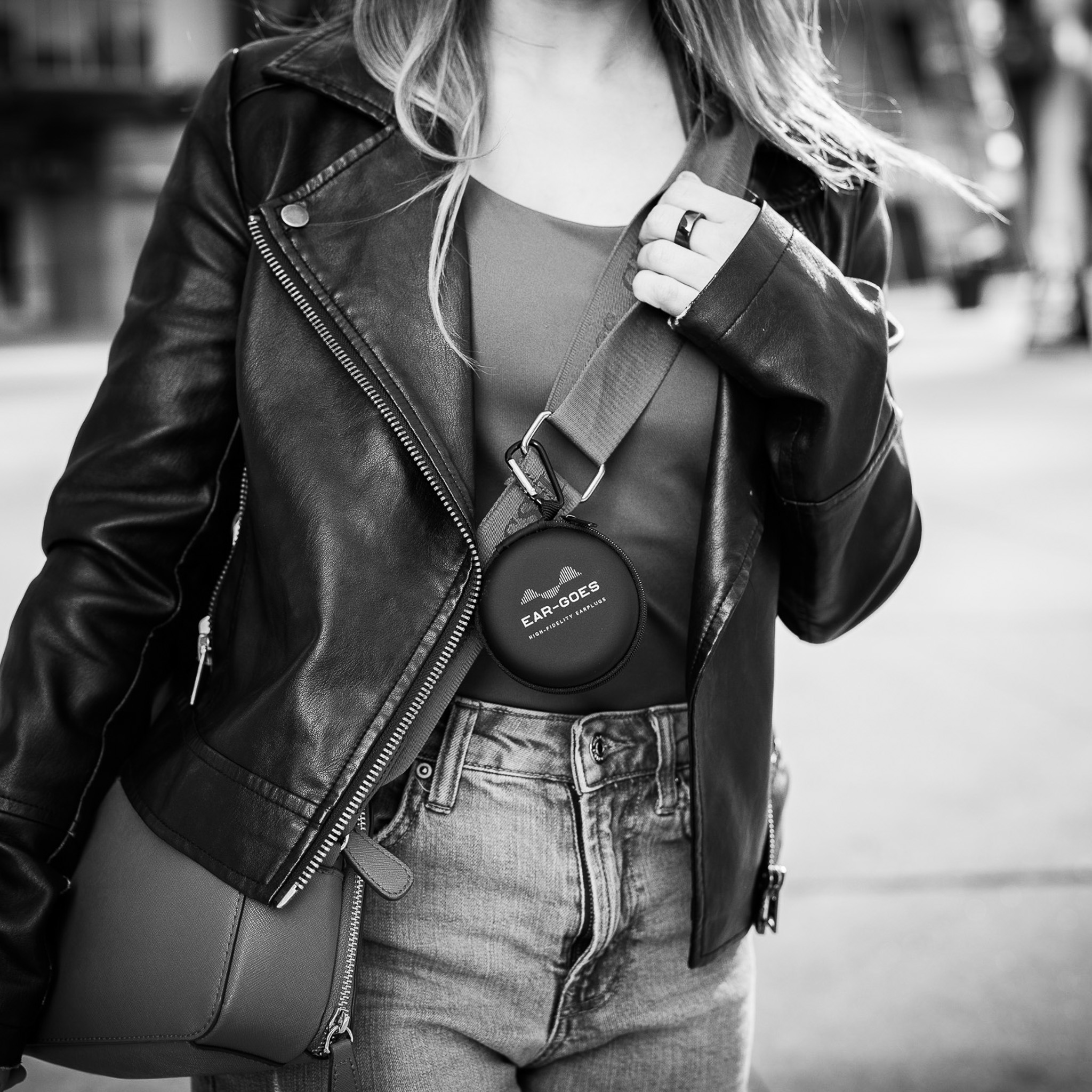 A woman wearing a purse with Ear-Goes earplug zippered carrying case clipped onto the strap