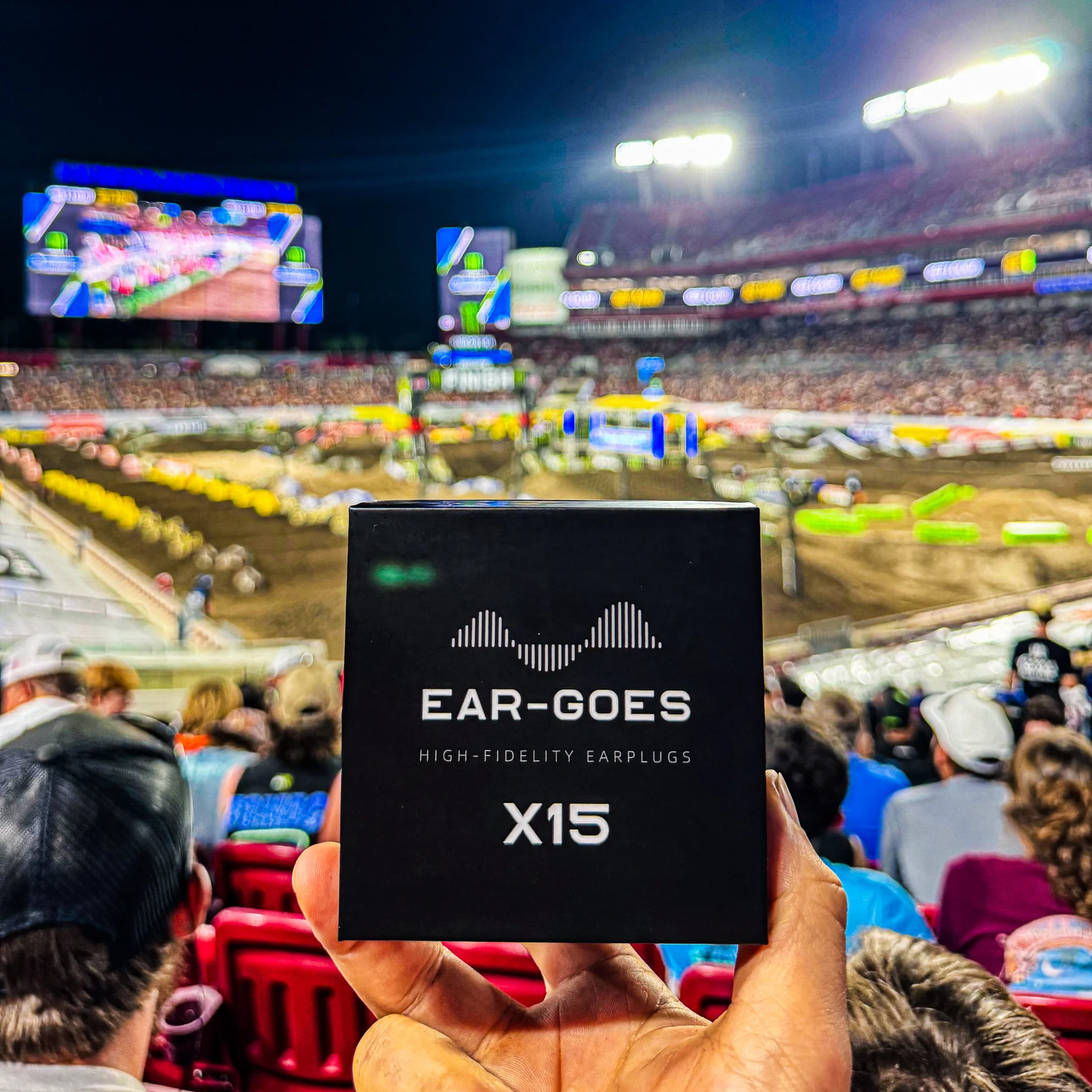 A hand holds a box of Ear-Goes earplugs at a super cross race event